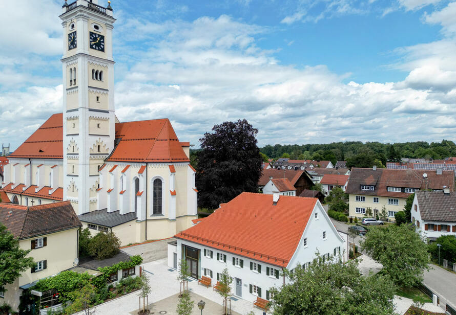 Drohnenaufnahme einer Kirche mit umliegenden Wohnhäusern in Türkheim. Übersichtsbild zur Darstellung von Ortsstruktur, Architektur und Umgebung.