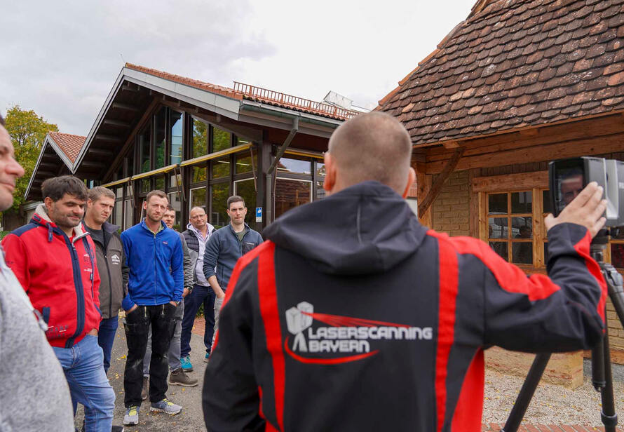 Praxisvorführung eines Laserscanners im Außenbereich mit Teilnehmern, Einblick in die Anwendung moderner 3D Vermessung im Holzbau und Bestand.