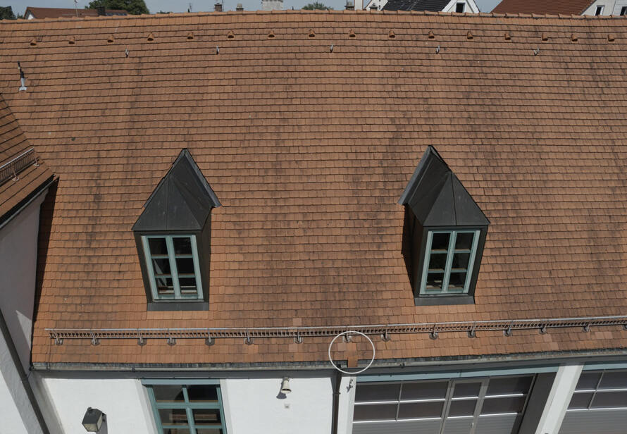 Drohneninspektion eines Wohngebäudes mit Fokus auf Dachfenster und Dachrinne. Kontrolle von Bauteilen zur Vermeidung von Folgeschäden und Wassereintritt.