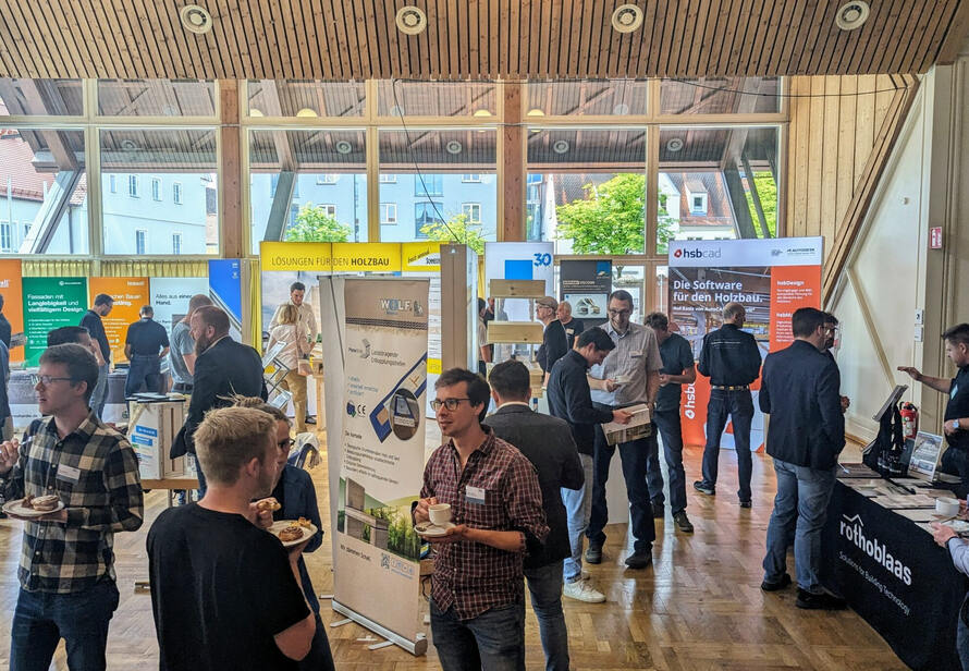 Aussteller und Besucher im intensiven Austausch auf der Holzbau Fachtagung. Fokus auf innovative Lösungen im Bauwesen.