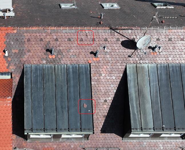 Dachcheck mit Drohne zur Erkennung beschädigter Dachziegel und lockerer Dachplatten auf einem Wohngebäude zur Überprüfung der Verkehrssicherheit.
