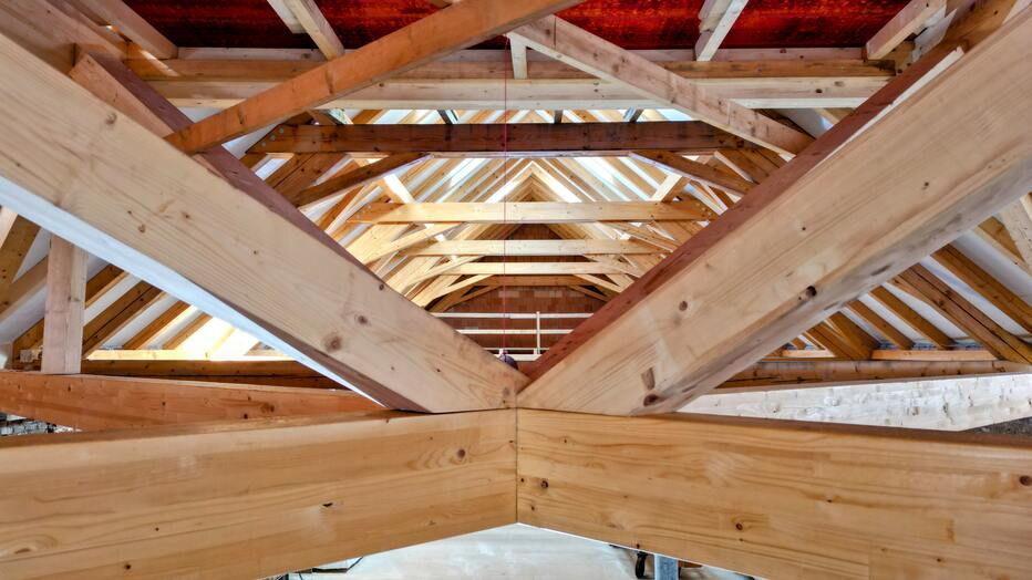 Luftaufnahme eines Holzbau Dachstuhls mit sichtbarer Holzkonstruktion während der Bauphase.