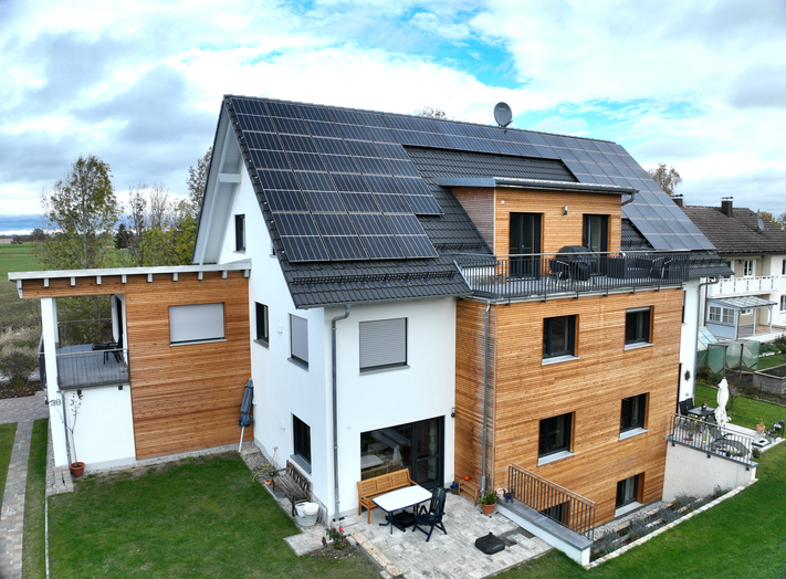 Drohnenaufnahme eines modernen Wohnhauses mit Photovoltaikanlage auf dem Dach.