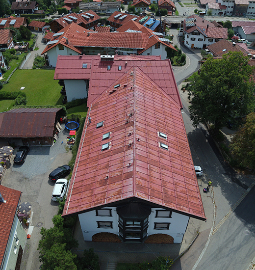 Drohnenbild eines Mehrfamilienhauses mit roten Blechdach