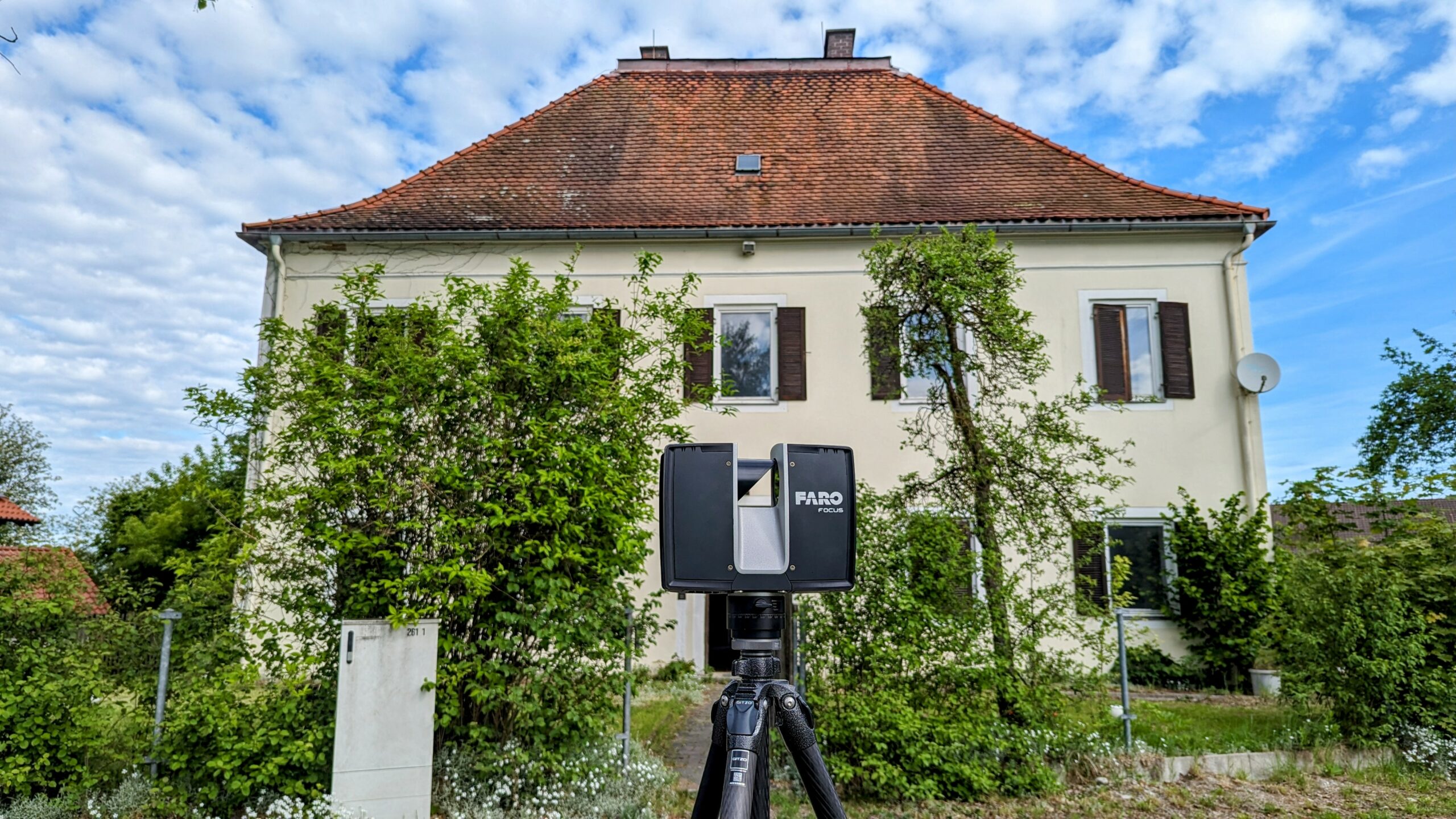 Pfarrhaus in Oberbayern und im Vordergrund ein FARO Laserscanner