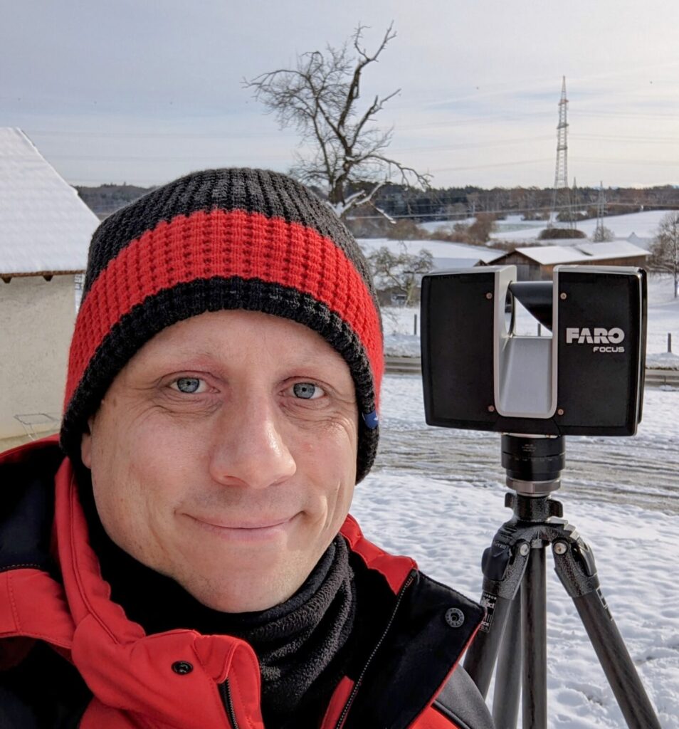 Matthias Scannt gerade mit sienem Laserscanner ein Haus in winterlicher Landschaft